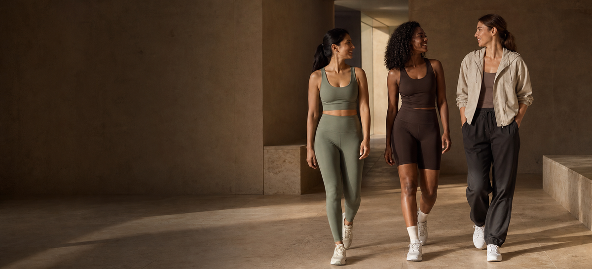 Three women in coordinated Cantera activewear and athleisure walking through a warm architectural studio